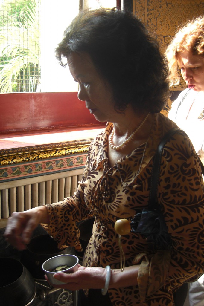 滿心虔敬的瓊齡媽媽，正往一百零八個缽投幣祈願。圖由張瓊齡提供